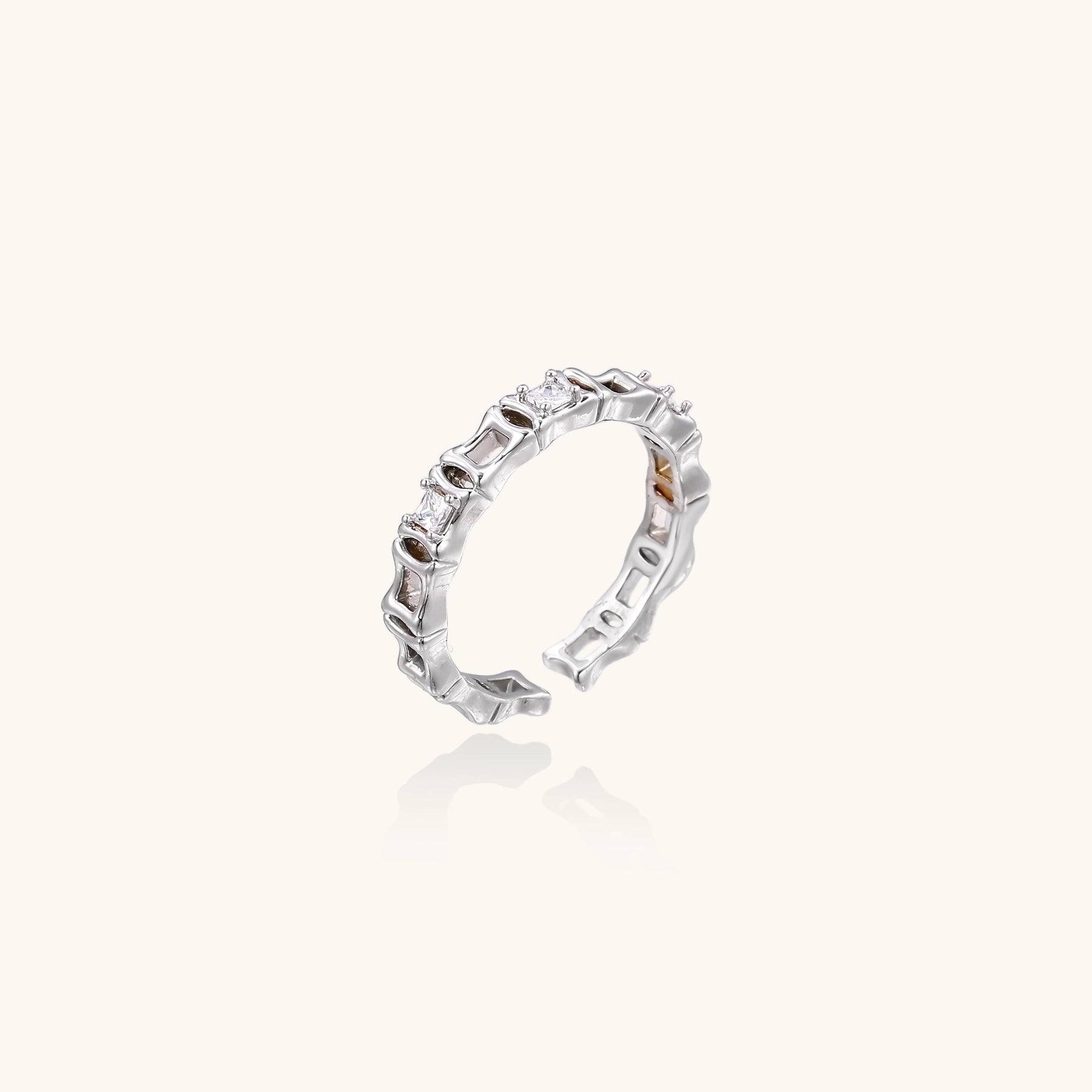 White gold plated ring with architectural lattice design and zirconia accents on cream background