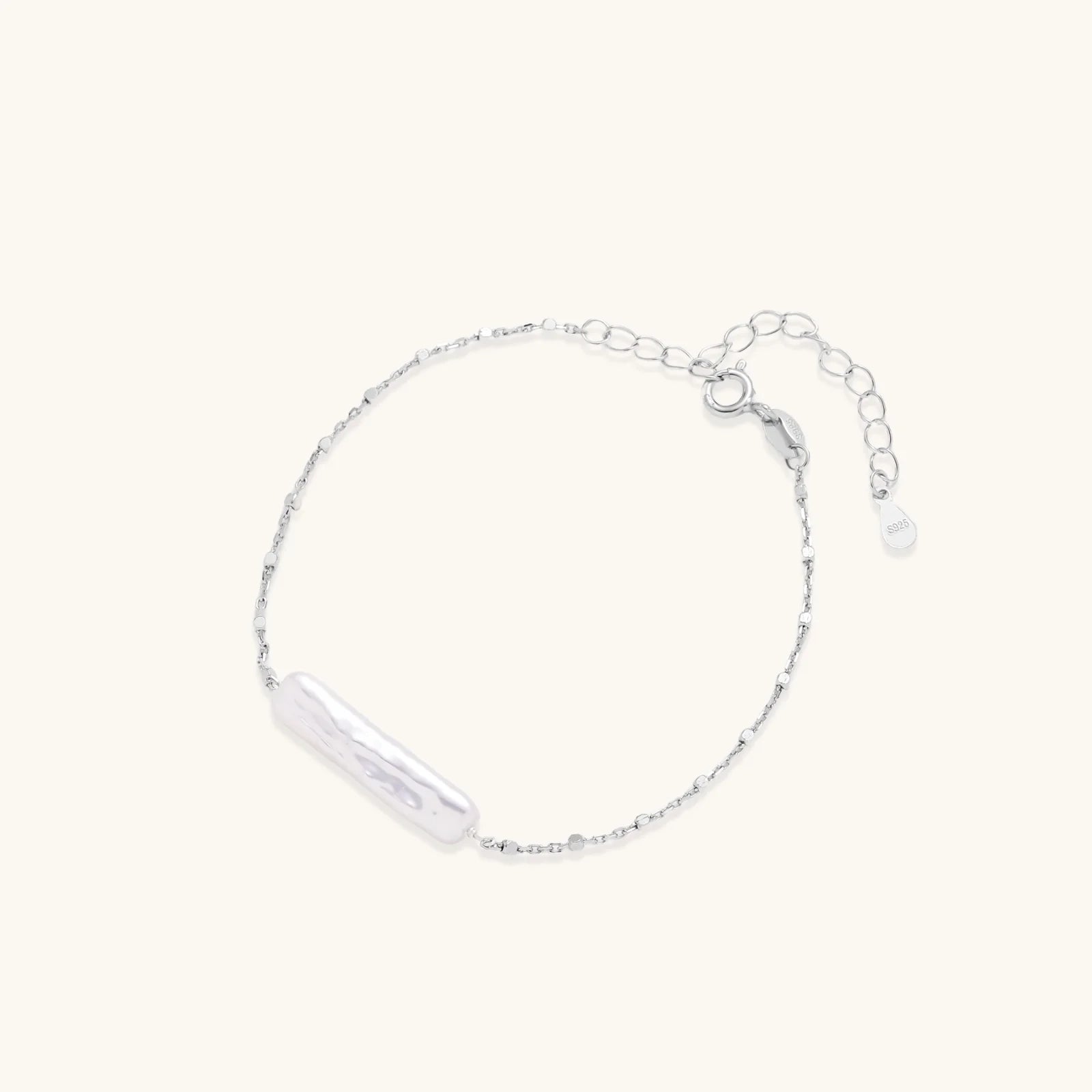Minimalist bracelet with iridescent baroque pearl on rhodium-plated sterling silver chain against cream background