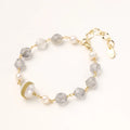 Bracelet with cloudy quartz beads, freshwater pearls, and gold-wrapped baroque pearl centerpiece on white background.
