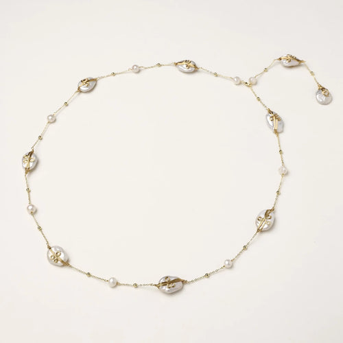 Long gold chain necklace with baroque pearls wrapped in leaf designs and small freshwater pearls spaced along the strand