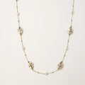 Long gold chain necklace with baroque pearls wrapped in leaf designs and small freshwater pearls spaced along the strand