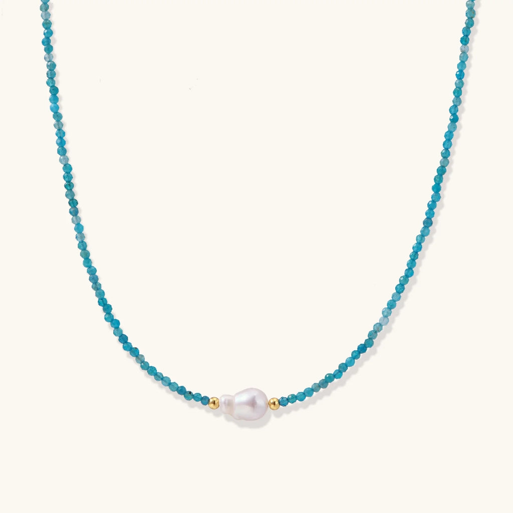 Delicate gold vermeil necklace with teal apatite beads and freshwater pearl on white background.