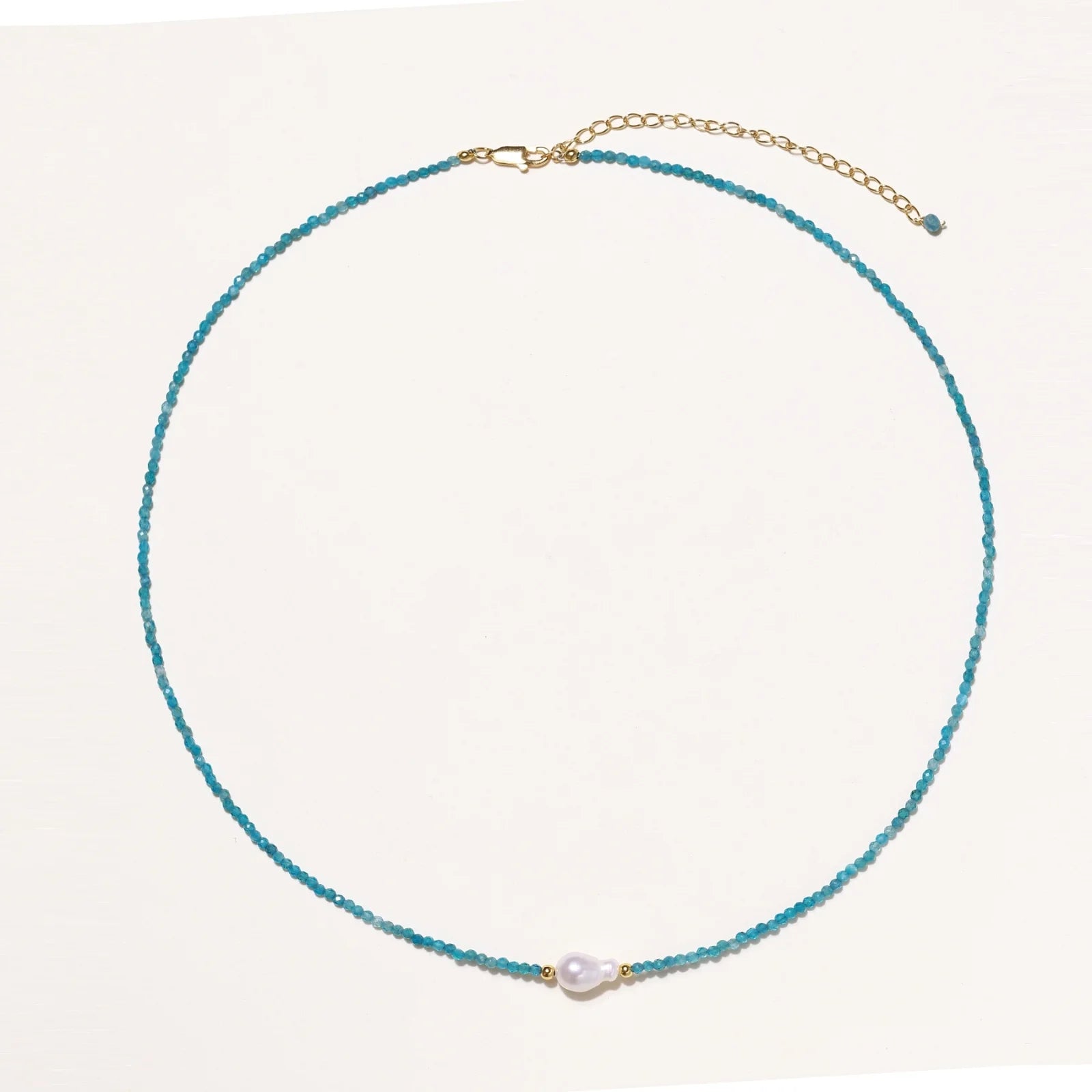 Delicate gold vermeil necklace with teal apatite beads and freshwater pearl on white background.