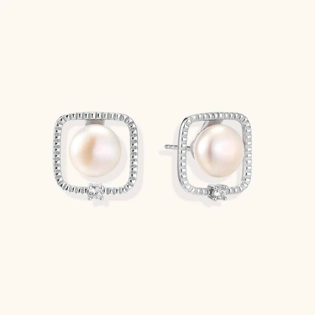 Rhodium-plated silver stud earrings with cushion frame, centered freshwater pearl, and tiny crystal accent