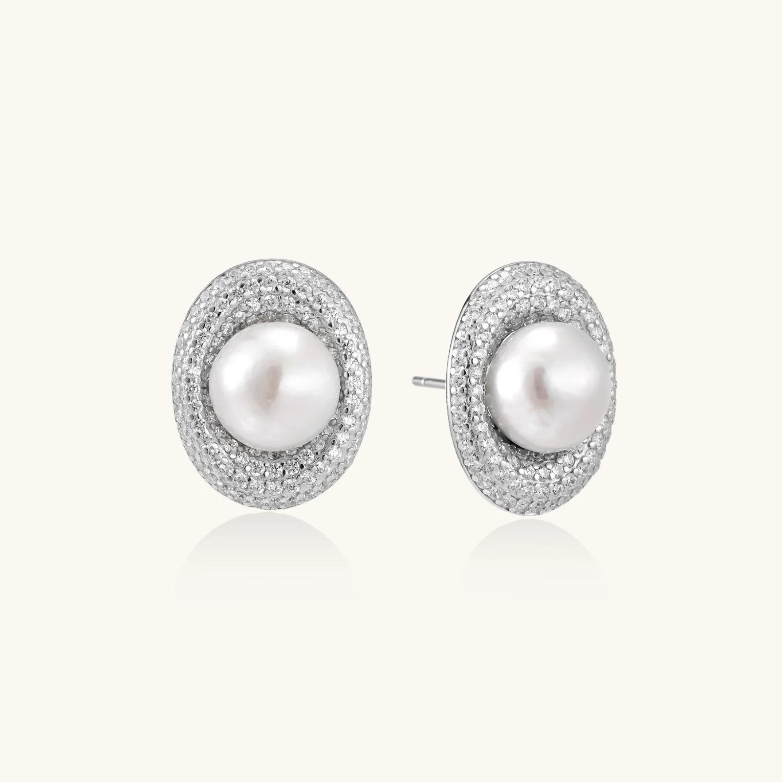 Oval rhodium-plated silver studs featuring freshwater pearls surrounded by pavé crystal halo on white background