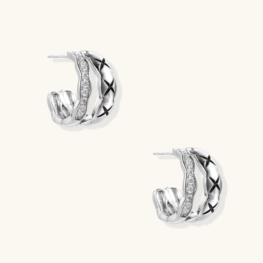 Triple-row white gold hoops with black X-pattern, twisted band, and pavé zirconia stones on white background.