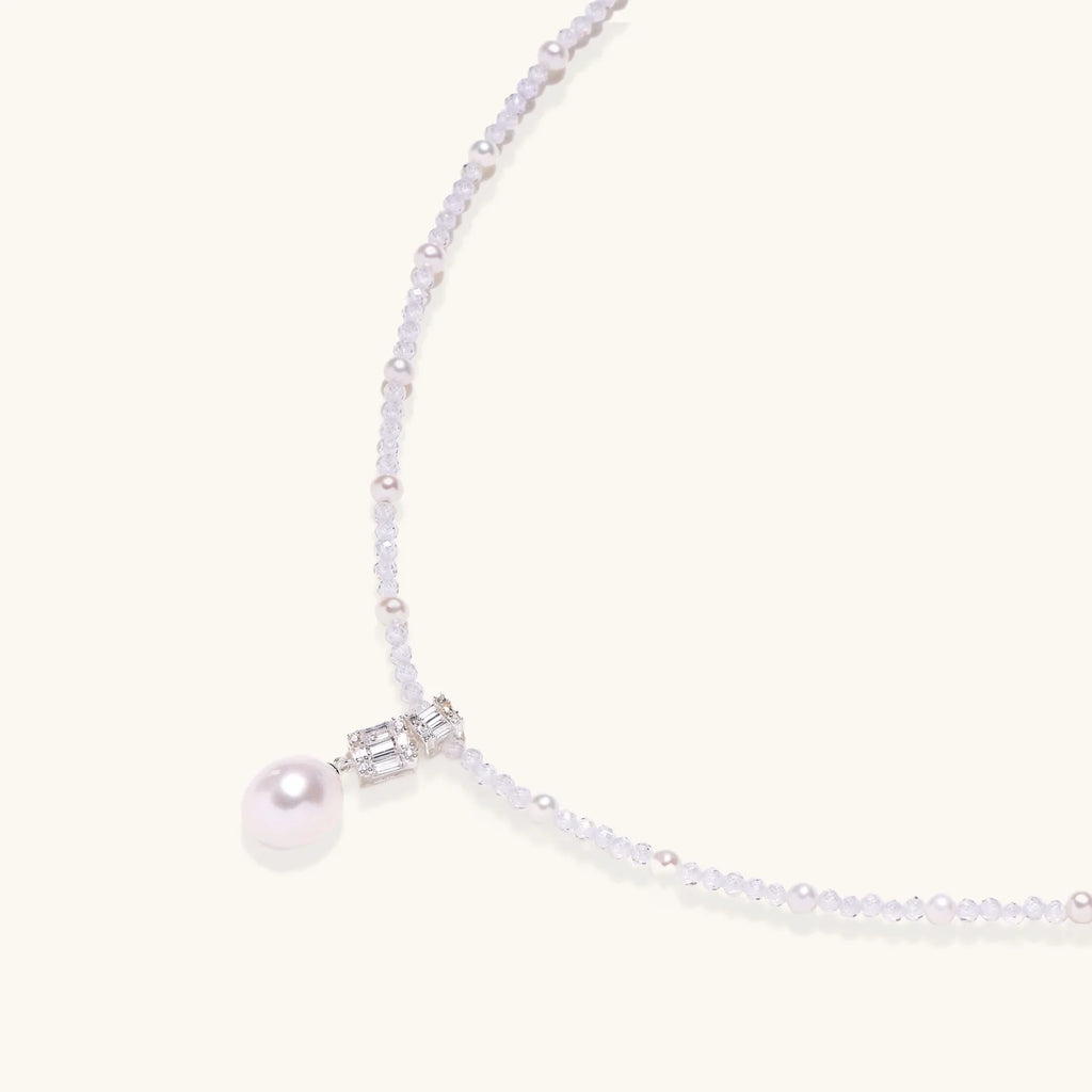 Dainty necklace with lavender crystal beads, freshwater pearls, geometric pendant, and large pearl drop on white background.