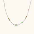 Delicate pearl necklace with pale green serpentine jade centerpiece and colorful agate beads on cream background