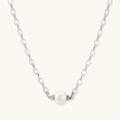 Dainty rhodium-plated silver chain necklace with centered 10mm freshwater pearl and crystal accents on cream background
