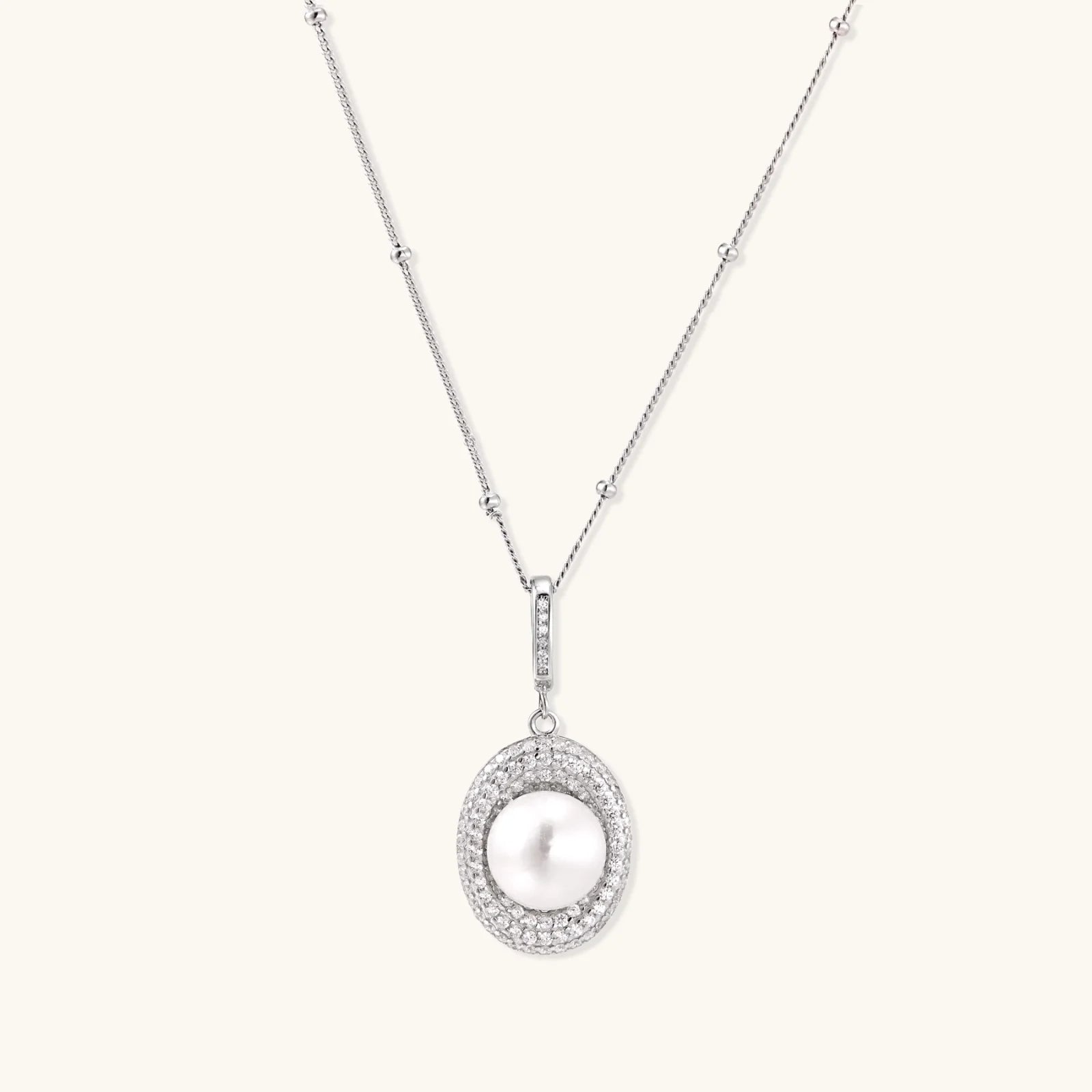 Oval sterling silver pendant with crystal halo surrounding a white freshwater pearl on delicate chain