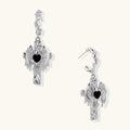 Silver-toned drop earrings with angel wings framing a black heart-shaped stone, white gold plated brass with S925 posts