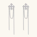 White gold plated baroque cross stud earrings with long cascading zirconia chains on cream background