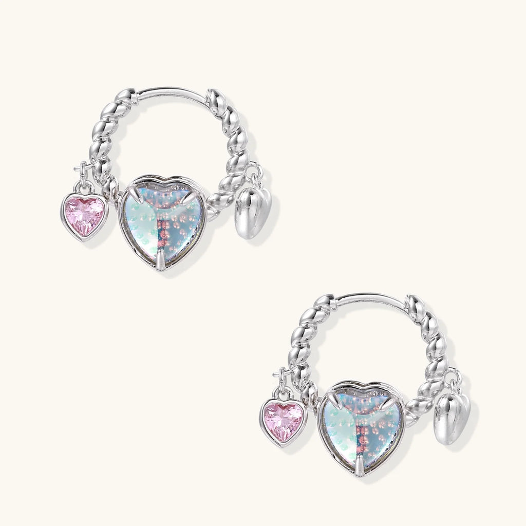 Silver chain hoop earrings with iridescent opal heart charms and pink zirconia accents on white background