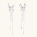 Elegant chandelier earrings with phoenix wing design, white pearls, and cascading silver chains on cream background