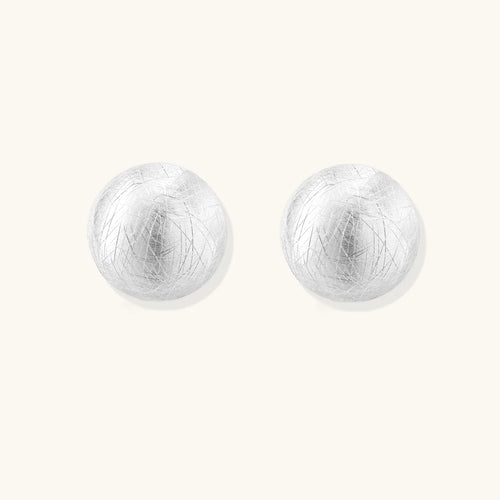 Brushed sterling silver half-dome clip-on earrings with textured surface against cream background
