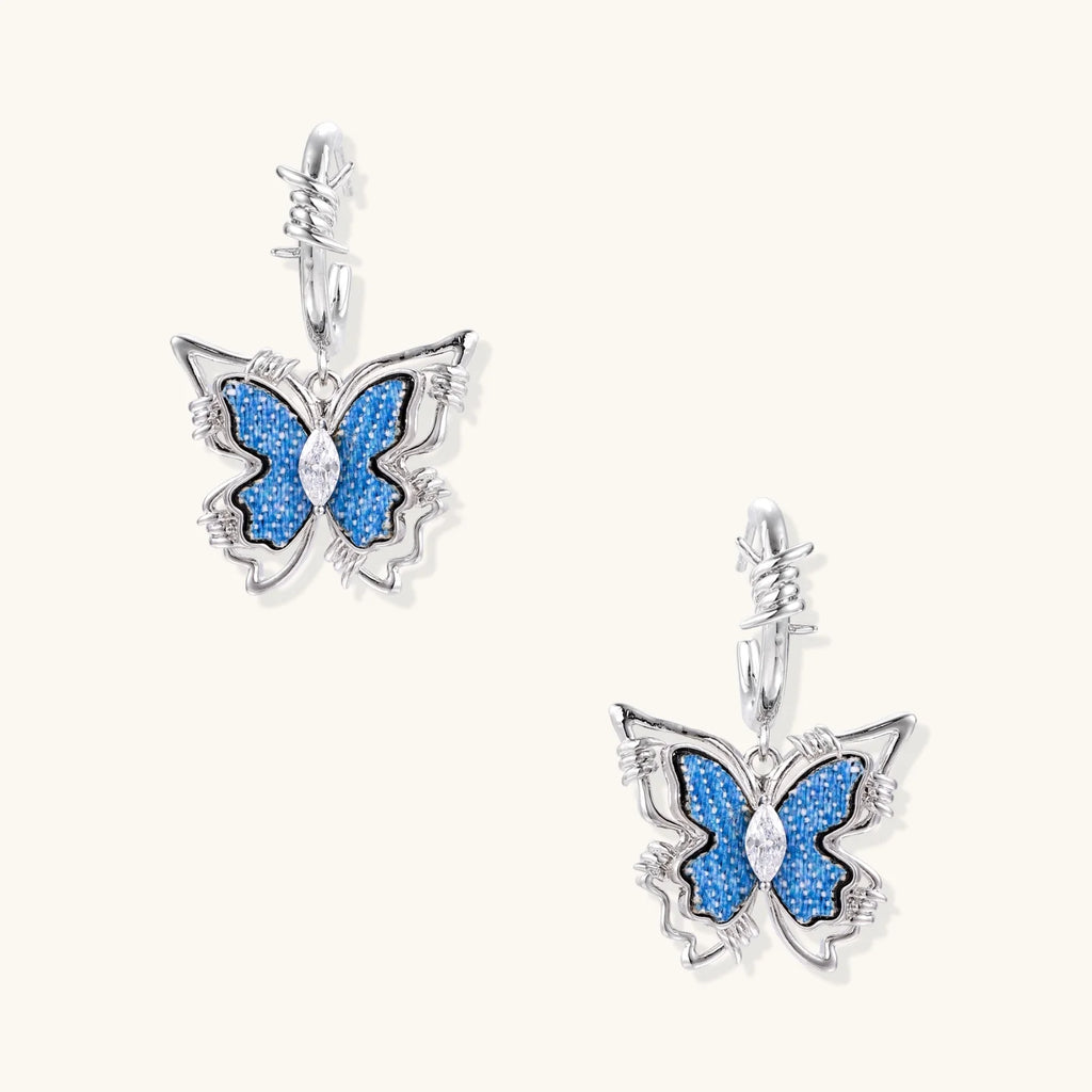 Silver hoop earrings with blue denim butterfly charms outlined in barbed wire design and central zirconia stone