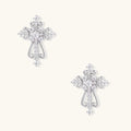 White gold-plated baroque cross studs with zirconia stones and ornate scrollwork on cream background.