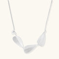 Minimalist sterling silver necklace with three brushed leaf-shaped pendants on delicate chain against white background