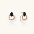 Gold drop earrings with oval lapis lazuli, crystal-paved frame, and iridescent mother-of-pearl teardrop on cream background