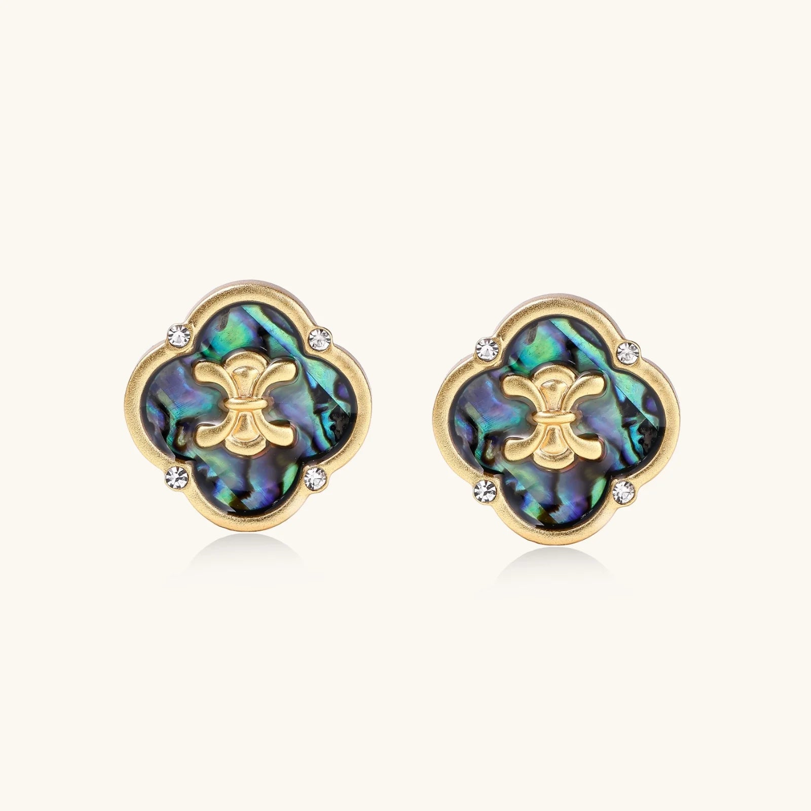 Gold quatrefoil stud earrings with iridescent abalone shell inlay and fleur-de-lis center, accented by four crystals