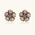 Gold-plated floral stud earrings with geometric zirconia crystals arranged in five-petal design on cream background