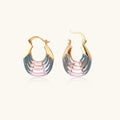 Gold hoop earrings with gradient blue-to-pink enamel in ribbed fan design on beige background
