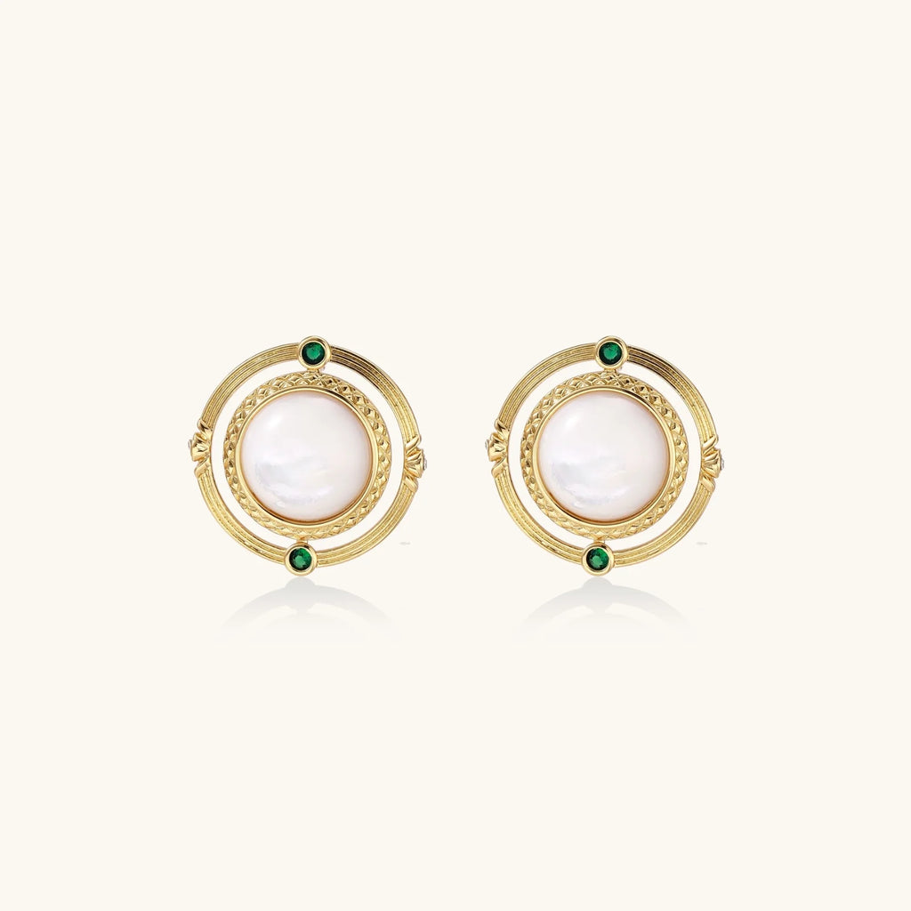 Circular gold stud earrings with iridescent mother-of-pearl center and green zirconia accents on cream background.
