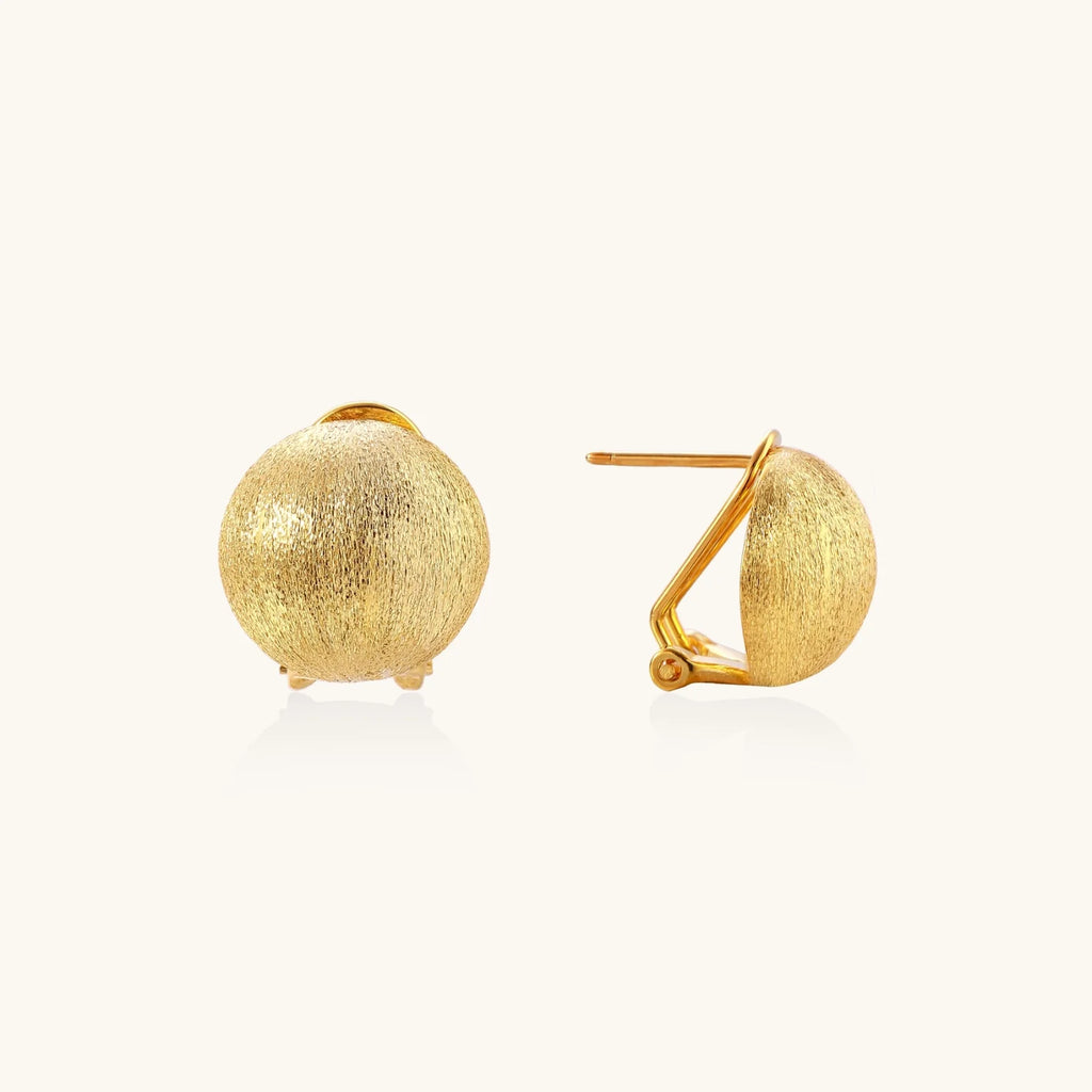 Pair of brushed gold dome earrings with clip backs showing textured matte finish on cream background