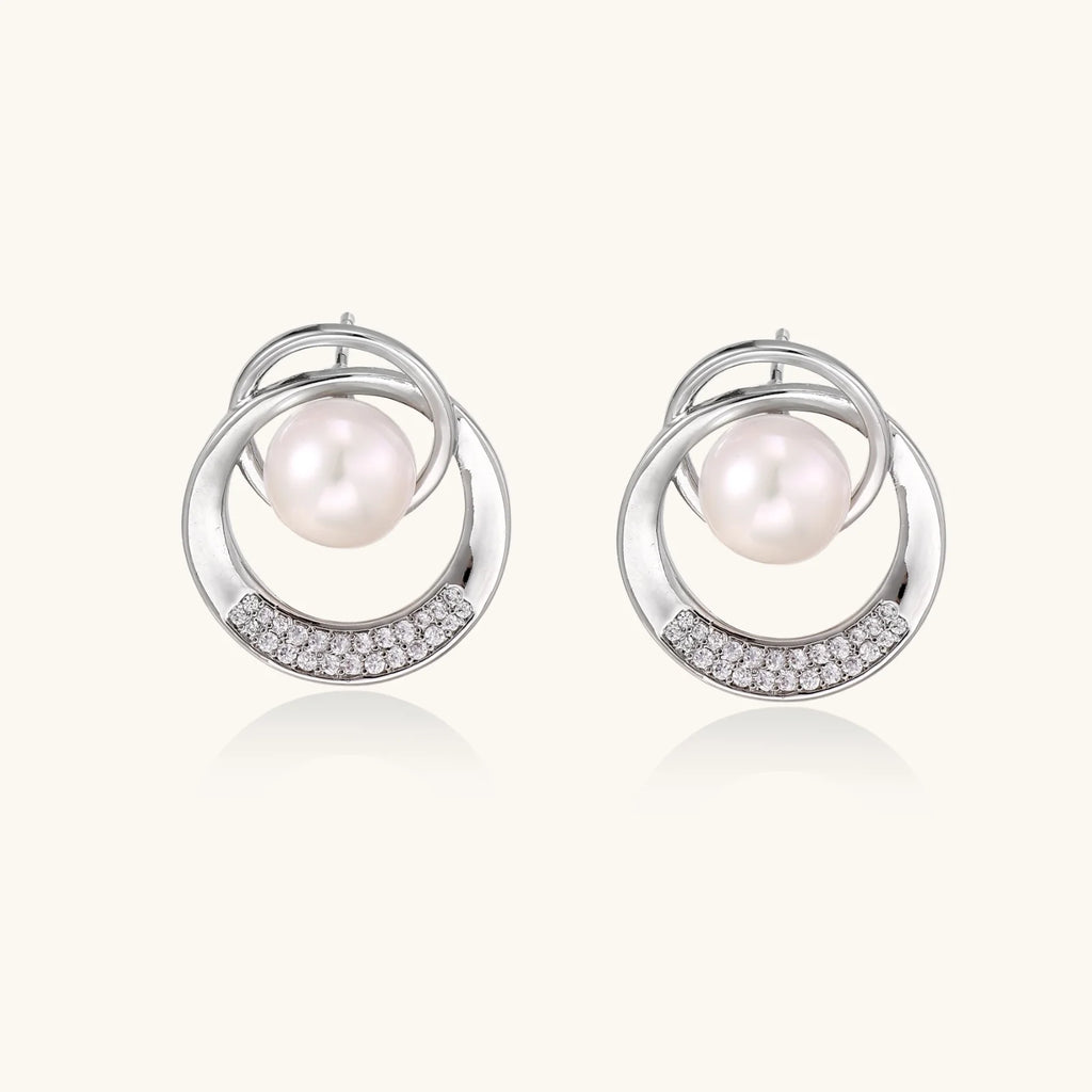 White gold-plated brass earrings with circular design, freshwater pearl center, and diamond accents