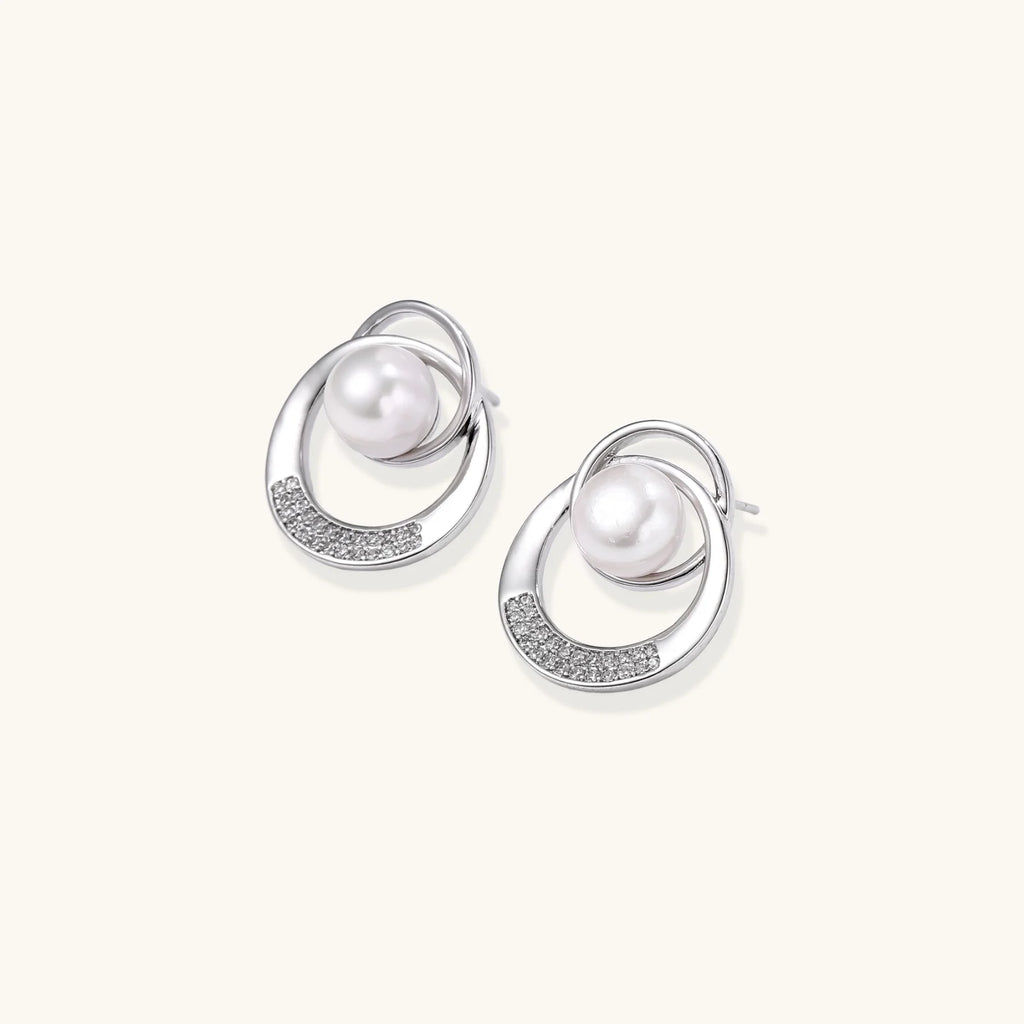 White gold-plated brass earrings with circular design, freshwater pearl center, and diamond accents