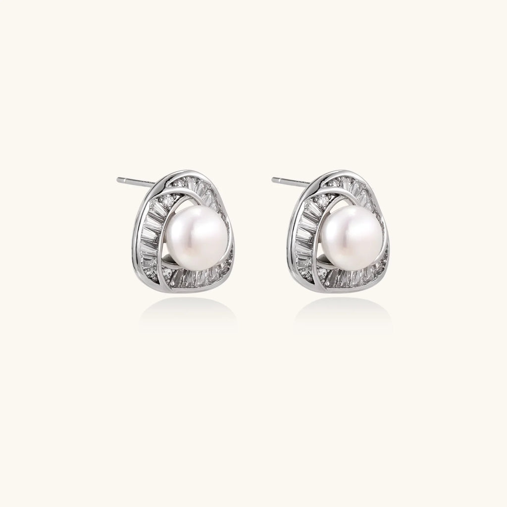 Triangular white gold plated stud earrings with central freshwater pearl and baguette-cut stones on white background