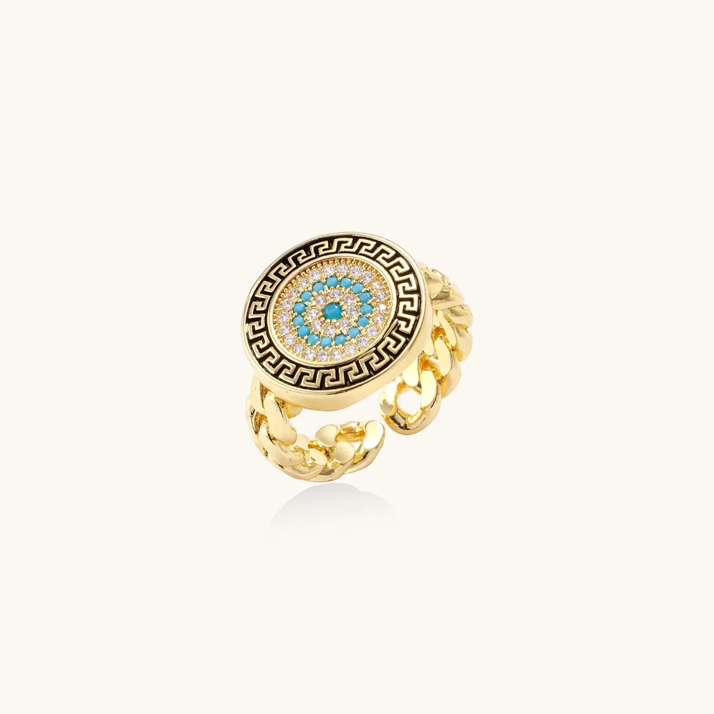 Gold chain ring with Greek key border and turquoise evil eye center on white background