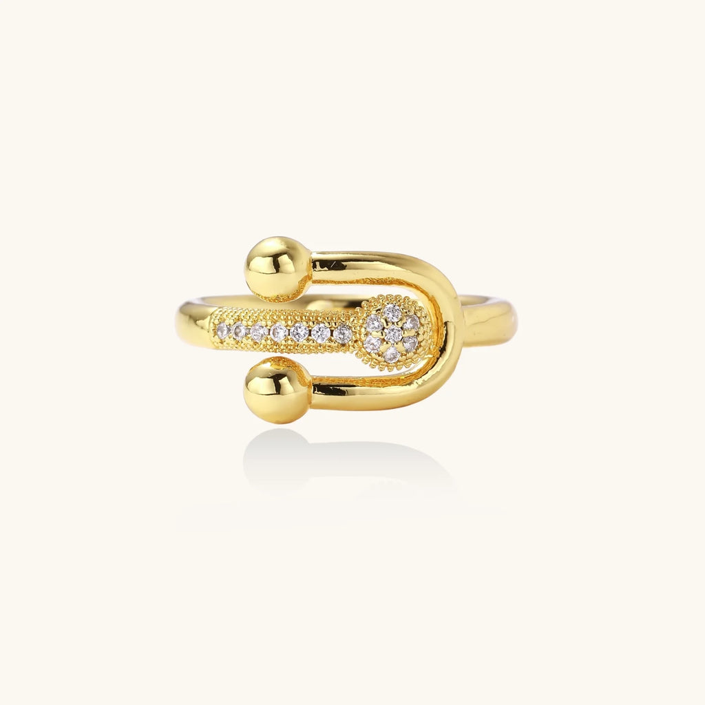 Gold-plated brass ring with safety pin design featuring pavé cubic zirconia stones and dual sphere ends