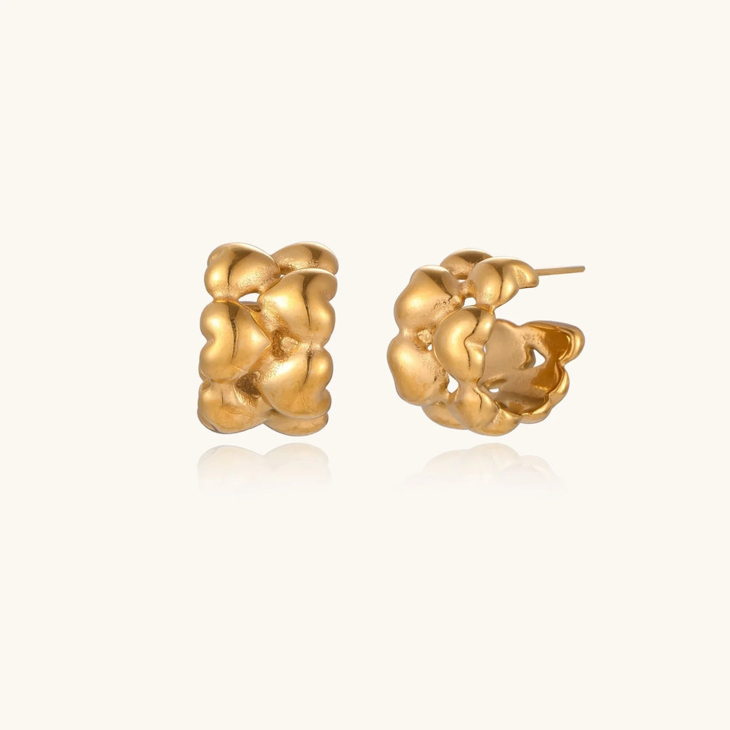 Close-up of gold-plated twisted rope huggie hoop earrings with brushed finish on white background.