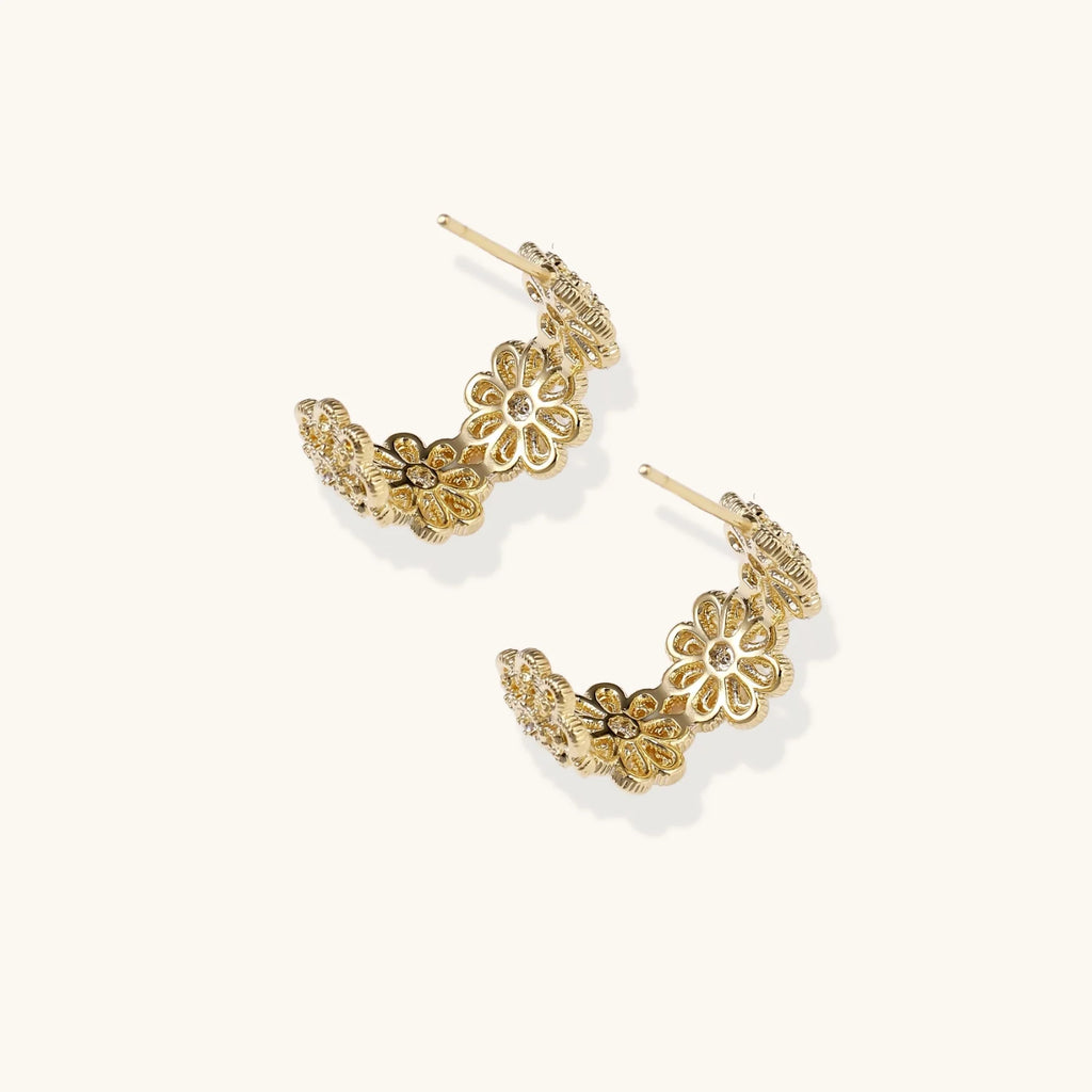 Gold hoop earrings with intricate three-dimensional floral filigree pattern in 14K gold plated brass on cream background