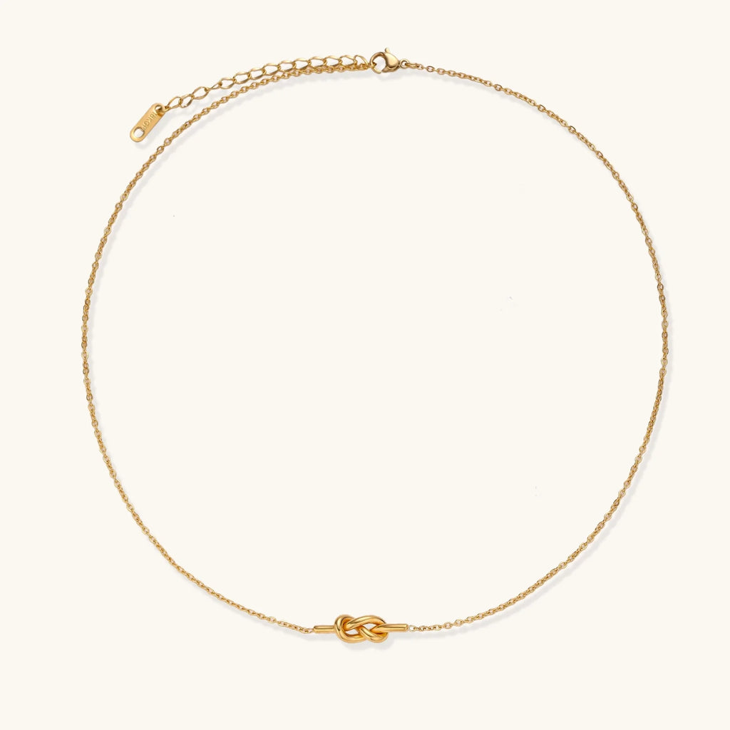 Dainty 18K gold plated necklace with infinity knot pendant on delicate chain against white background