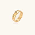 Close-up of an 18K gold-plated twisted band ring with dimensional braided pattern on cream background.