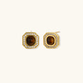 Gold-plated octagonal stud earrings with brown tiger's eye centers and cubic zirconia border on cream background.