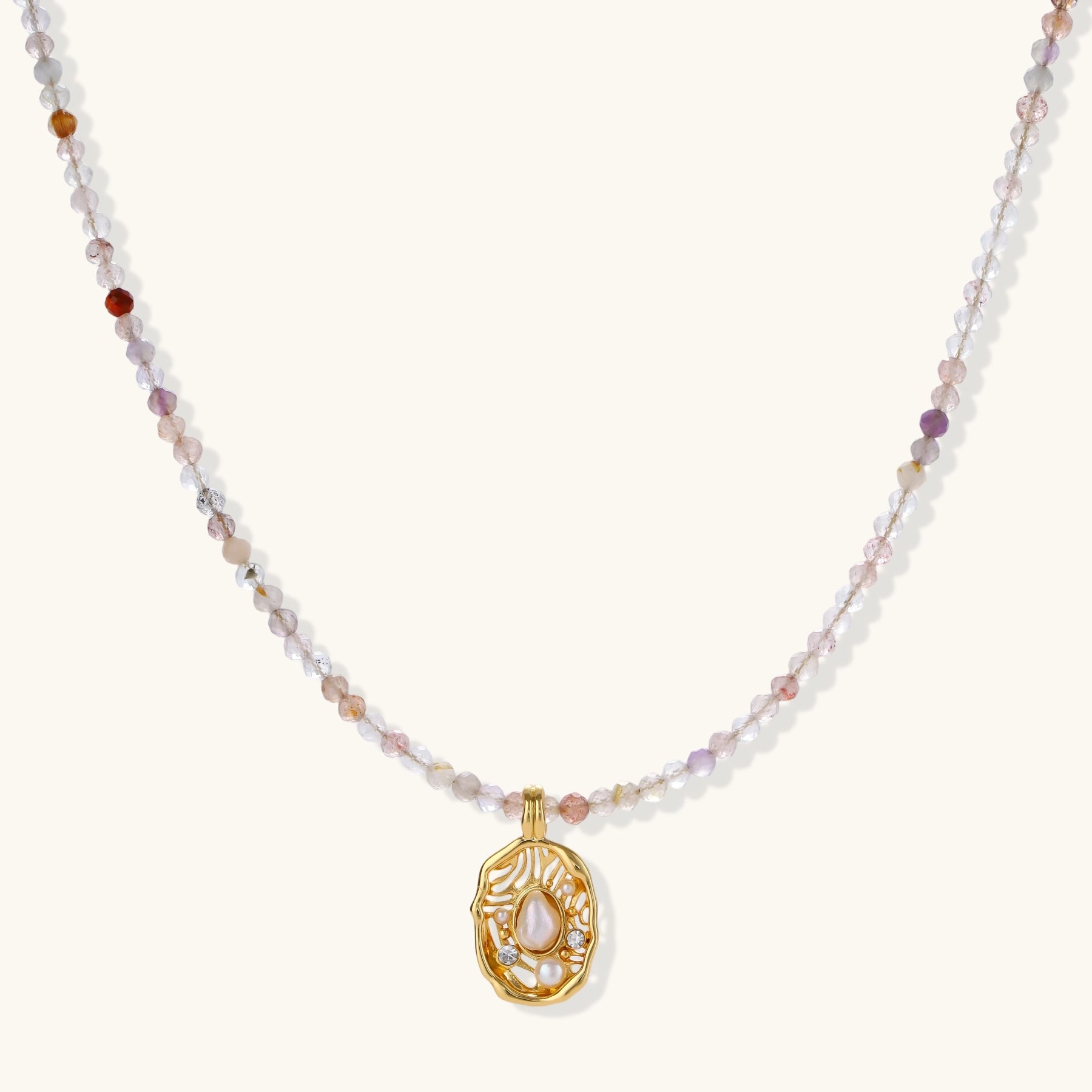 Delicate gold-plated necklace with mixed gemstone beads and ornate oval pendant on white background